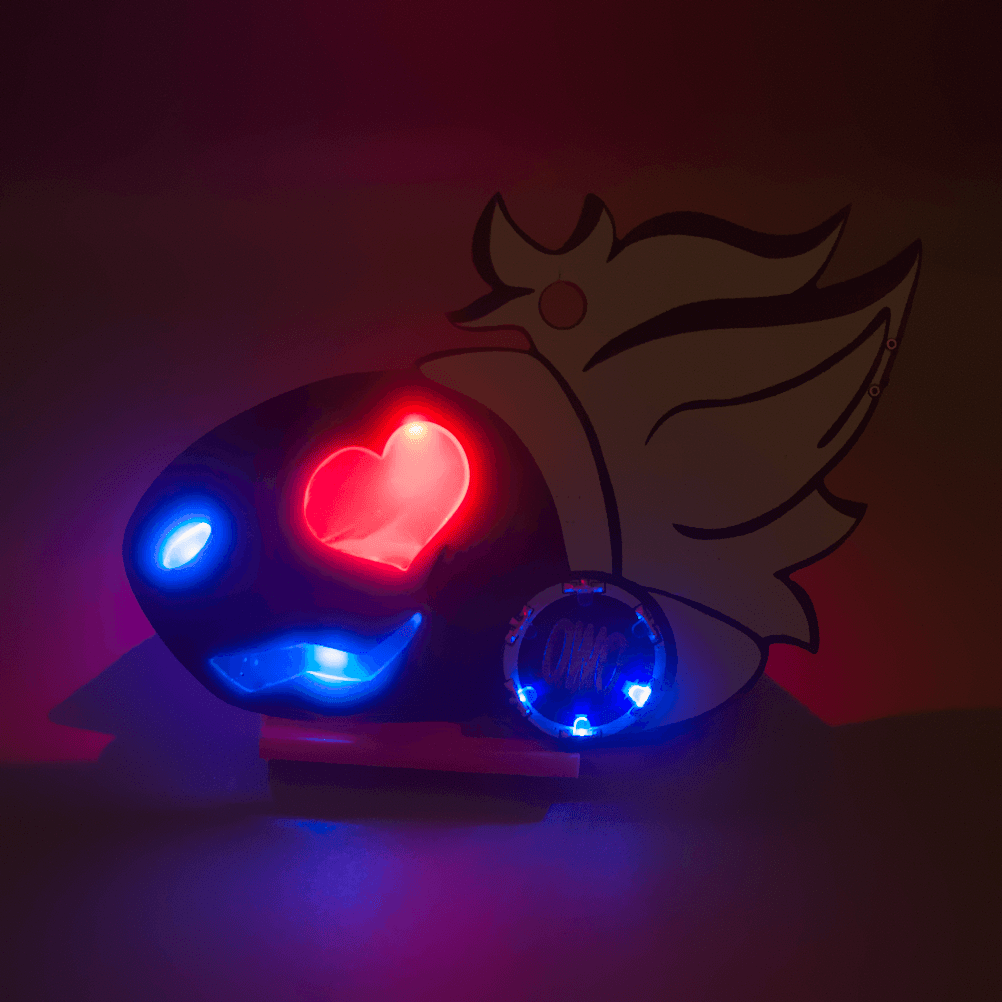 A brightly illuminated PCB badge in a dark environment. The badge is in the shape of a protogen's head. They have a heart-shaped eye which is red, and a blue mouth and nose. The facial features are illuminated. They also have a circle of LEDs on their cheek with a copper Lepi Labs logo in the center. They have white hair.
